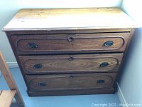 Front view of vintage wooden dresser with three drawers showing drawer handles and overall condition.