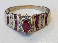 Oblique front view showing marquise ruby center, diamond halo and ruby channel shoulders
