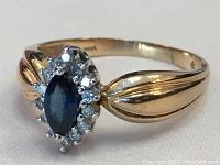 Front view of ring showing marquise sapphire center and halo of round diamonds