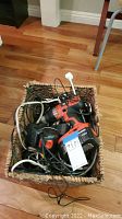 Wicker basket filled with assorted tangled electrical cords and a cordless drill.