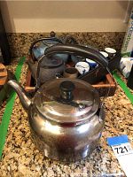 Metal tea kettle with glass lid on countertop