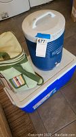 Two Rubbermaid coolers stacked and a soft insulated lunch bag with striped pocket on top.