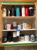 Full view of cupboard shelves showing an assortment of cups, coffee mugs, travel mugs, and water bottles in different colors and materials.