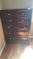 Front view of dark wooden 5-drawer dresser showing drawer arrangement and metal knobs