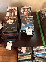 Top view showing stacks of DVDs including 'Superbad', 'The Brothers', 'The Tudors' and others on a wooden table.