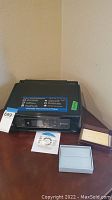 Epson printer/scanner unit with installation CD and two small boxes on table.