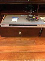 Front view of Sony DVP-NS575P CD/DVD player resting on wooden furniture, with bundled AV cable on top.