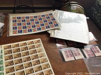 Photo showing multiple full sheets of Canadian stamps in protective sleeves on a table, including sheets with wildlife and other themes.