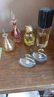Four perfume bottles of various glass styles and two small silver-toned swan figurines arranged on a wooden surface, showing different angles and details.