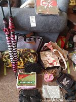 Two umbrellas, six purses, and two handbags arranged in front of a couch