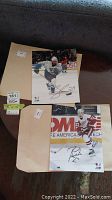 Two signed 8x10 hockey pictures displayed on table with envelope beneath