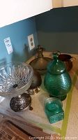 Six assorted glass and metal bowls and serving containers displayed on a countertop, showing variety in color and material.