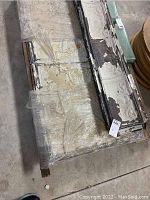Top view of several rectangular antique tin ceiling panels stacked and shrink-wrapped, showing paint wear and embossed details.