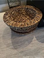 Three woven round storage baskets stacked or nested, placed on carpet.