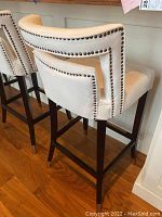 Rear and side view of two stools showing upholstery and nailhead trim on open back design