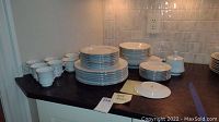 Full view of arranged china pieces including plates, cups, saucers, sugar bowl and creamer on counter