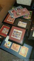 Overview of multiple framed and matted Disney collectible stamps sorted on the floor.