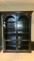 Front view of two-section Ethan Allen wooden bookcase showing multiple shelves, crown molding, fluted columns