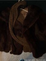 Four dark fur shawls draped on hanger together.