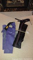 Two pairs of leather motorcycle chaps: black Harley Davidson and purple fringed pair, laid flat on carpet.