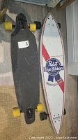 Two longboards side by side, showing top and bottom designs and wheels.