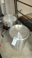 Photo of cooking pot with lid and frying basket on propane burner frame