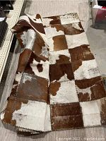 Patchwork leather hide rug made from stitched cowhide squares, brown and white mottled pattern.