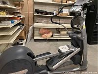 Side view of grey Precor stair stepper machine showing foot platforms, main housing, and handrails.