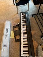 Keyboard and stand box on floor next to chair and table leg