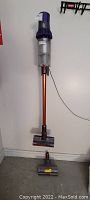 Dyson V10 cordless vacuum mounted on wall dock with two cleaner heads on floor