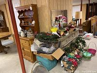 Wide shot showing several Christmas wreaths, Santa and angel figures arranged on furniture along with baskets and other decorative items