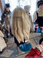 Group of dolls displayed near window, showing varied styles, clothing, and dolls with stands.