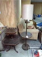 Wide view of the vintage floor lamp with attached round wood table and adjacent octagonal two-tier wooden side table in basement setting.