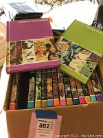 Photo showing 15 Childcraft books in a box with colorful spines and illustrated covers, along with history magazines placed above them.