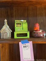 Shelf with three coin banks: Snoopy house bank, green Uncle Sam register bank, and wooden duck bank.