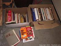 Two full boxes of assorted cookbooks and food reference books including health-related and culinary history titles, contents spilling slightly out of boxes