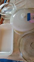 Two white opaque Pyrex dishes with one lid and two clear glass round dishes with lids