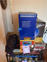 Five boxed items arranged on a shelf: Thunderbolt Plasma Sphere, Spaceship Gyroscope, Animal Clench, Camaro Z28 model, and Nintendo Entertainment System Action Set.