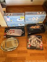 Overall view of all trays showing 4 Teeter Tray boxes, 2 silver-plated trays, and one Christmas platter in box, arranged on floor.