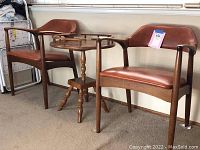 Overview of two armchairs flanking round accent table against wall