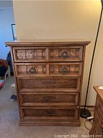 Front view of a medium brown wooden tall dresser with six drawers and decorative square inlay on upper drawers