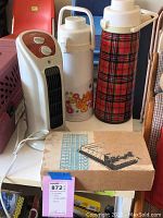 View of two vintage thermoses, the space heater and boxed Hot Dogger heater on white surface showing all items together
