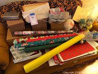 Photo showing a collection of wrapping paper rolls, gift boxes, and tissue paper on a couch