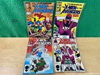 Full view of four comic books from the series 'The X-Men Vs. The Avengers' arranged side by side on green and wood backgrounds.