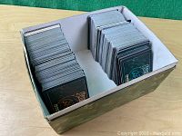 Two large stacks of Jyhad collectible cards in a box, showing card backs and overall condition.