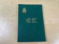 Cover of the green hardcover stamp album with gold embossed title and crest