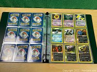 Binder open showing a page with 9 clear sleeve pockets (backs) and facing page with 9 Pokemon cards including Dark Hypno, Tangela, Bellossom, Phanpy.