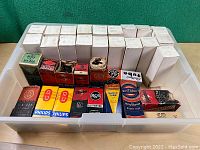 Top view of plastic bin filled with vintage radio vacuum tubes in original branded boxes including Philips, RCA, Rogers, GE and others.