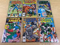 Six Captain America comic books, issues 307 to 312, displayed on a wooden surface with colorful covers featuring various Marvel characters.