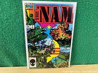 Front cover showing full comic book in protective sleeve on green background, with visible colorful battlefield themed artwork and clear Marvel branding.